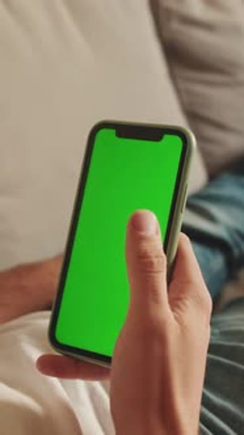 Close-up of the hands of man lying on sofa using mobile phone