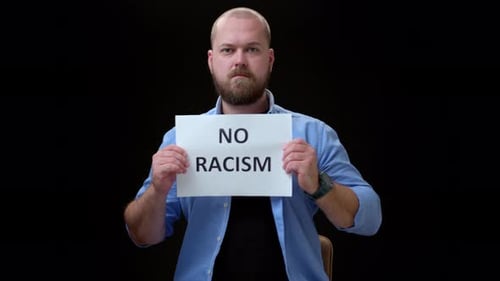 Bald Bearded Man Shows Inscription No to Racism Guy in Blue Shirt on Black Background at Single