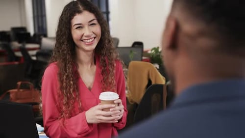 Two happy diverse creative colleagues in discussion in casual office, slow motion