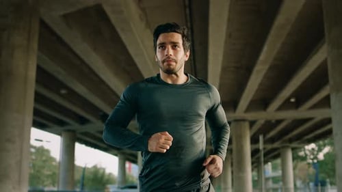 Athletic Young Man in Sports Outfit is Jogging in the Street. He is Running in an Urban Environment