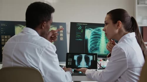 Doctors Examining X ray Scans on Computer and Tablet in Modern Clinic