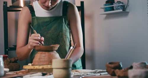 A female ceramicist is creating a new pottery in the workshop. Asian woman is enjoying pottery work.