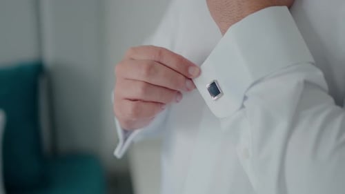 Man Fastens Cufflink on Shirt Sleeve Close Up