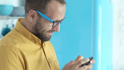 Man in mustard shirt using a smartphone
