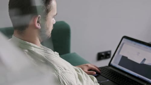 Happy Young Man Wearing Glasses and Smiling As He Works on His Laptop to Get All His Business Done