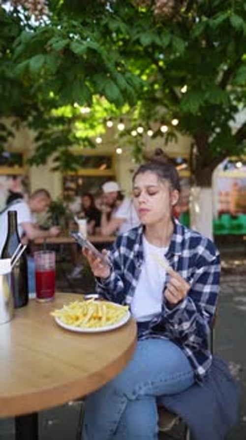 The Summer Café Terrace Scene Captures a Girl Savoring French Fries with Delight
