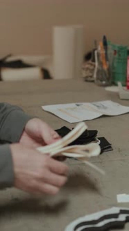 Craftsperson Arranges Fabric Pieces on Workbench, Close Up