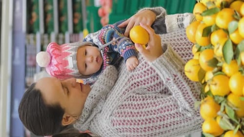 Mother with Baby Buying Lemons at Grocery