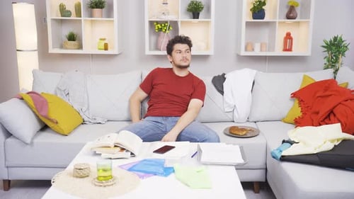 Young Man Relaxing on Sofa Surrounded by Mess