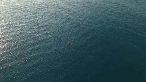 Aerial View A Lone Kayak Glides Across the Calm Open Sea with Gentle Ripples Forming Behind As the