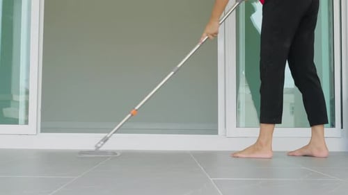 Woman Mops the Indoor Floor Cleaning the Front Area of Her Home with a Mop and Rag Housewife