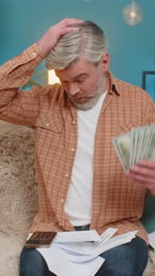 Man Calculating Finances at Home with Cash