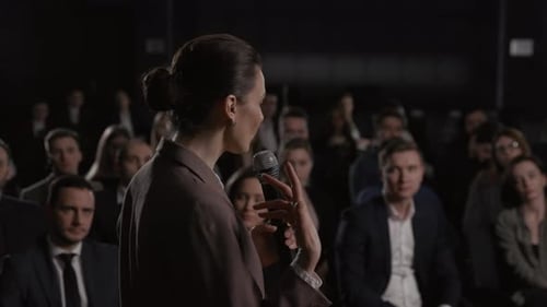 Woman Speaking at Conference to Large Audience