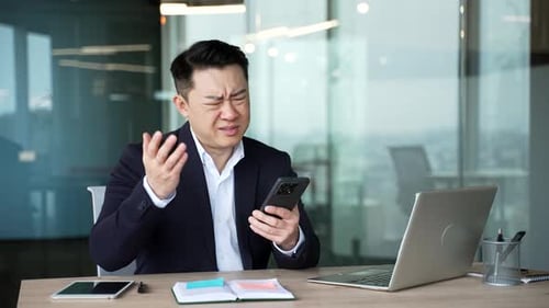 Businessman Looking at Phone with Frustrated Expression