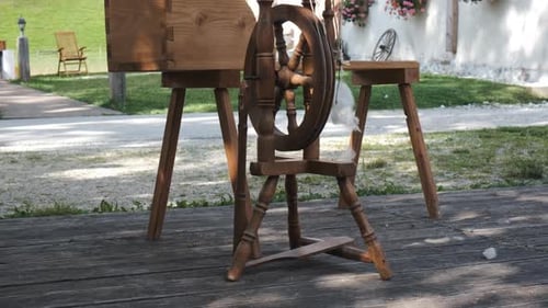 Vintage wooden spinning wheel, traditional Alpine house in background