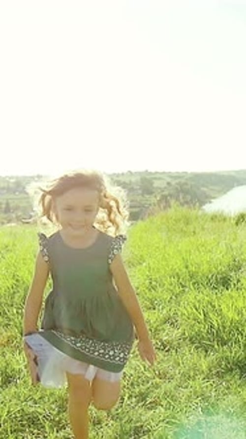 Child Runs Joyfully Through a Sunny Meadow Near a River in the Afternoon