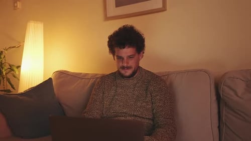 Young Adult Using Laptop on Couch at Home