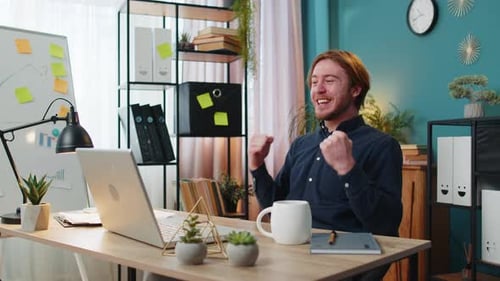 Man Celebrating Success While Using Laptop at Desk
