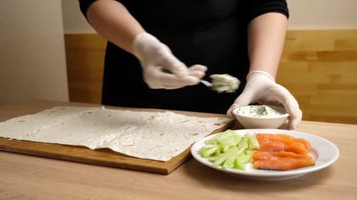 A layer of prepared cheese is placed on the pita bread. Preparation of roll with fish and vegetables