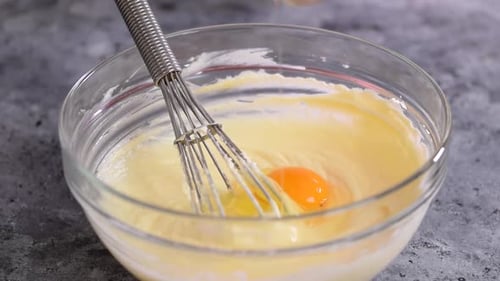 A Woman Adds an Egg to the Cream Cheese Mixture