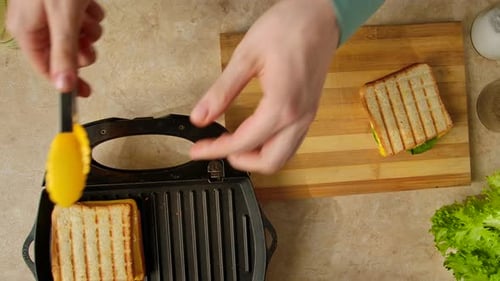 A Woman Takes Hot Sandwiches Off the Grill