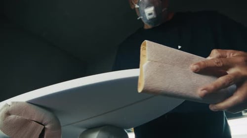 Surf board factory. Adult male shaper creates the surfing board on the factory
