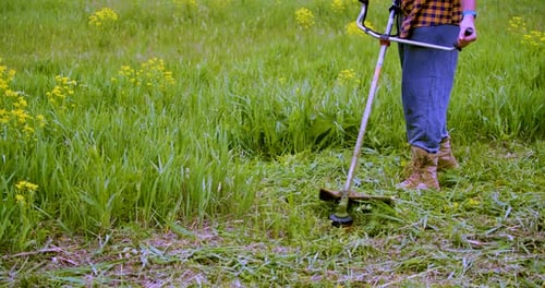 Closeup of a Man Cleaning Grass with a Trimmer