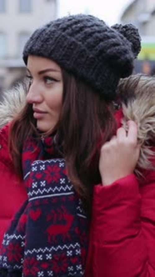 A Cheerful Woman in Winter Fashion Smiles Warmly on a Busy Street