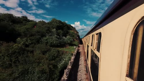 Side View of a Retro Yellow Train Running on Rails in a Picturesque Location Near Mountain
