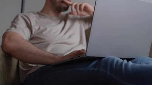 Adult Using Laptop while Relaxing on Couch