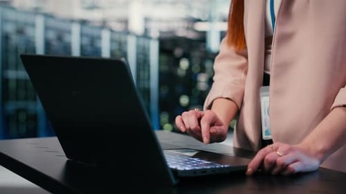 Close Up of Engineer Typing on Laptop in Server Farm