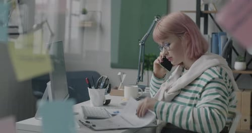 Young Lady Speaking on Mobile Phone Checking Documents and Using Computer Working in Office