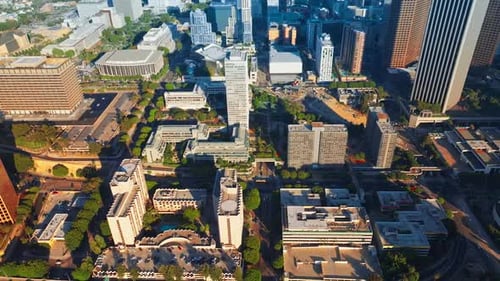 Rising above sunlit Los Angeles downtown. Crazy traffic on the roads of metropolis from aerial view.