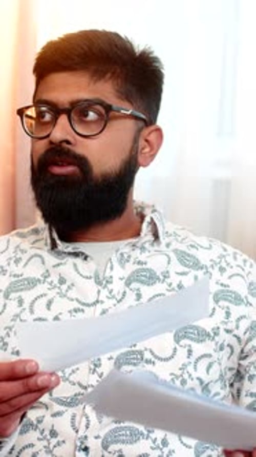 Man Reads Document Indoors Holding Paper