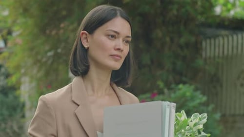 Unemployed Businesswoman Walking with Office Stuff along Street
