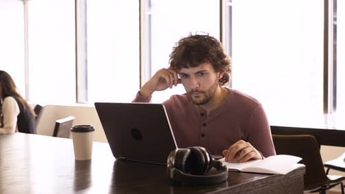 Nachdenklicher junger Geschäftsmann, der 2024 Jahre im Büro am Laptop arbeitet