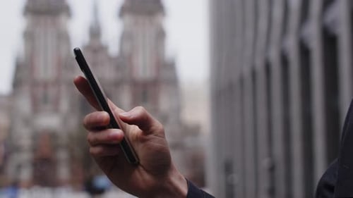 A Man Standing on the Street is Typing a Message on His Phone Cropped View of a Male Hand Quickly