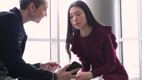 Businesswomen talking meeting in office lobby using smart phone technology