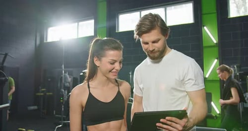 Waist Up Portrait View of the Calm Sports Girl Looking Something at the Tablet Screen with Her Coach