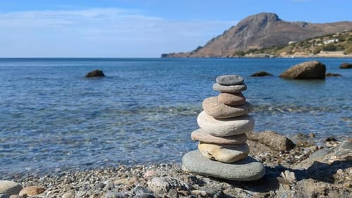 Pile of stones on the beach by the sea, mountain background