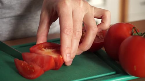 Woman Slicing Tomato on Green Cutting Board