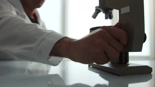Scientist Adjusting a Microscope in a Bright Lab