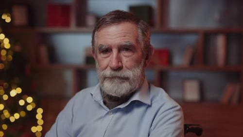 Smiling Man with Beard Sits near Christmas Tree
