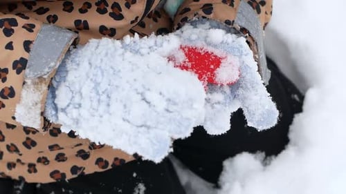 Das Kind legt rote Herzen in den Schnee. Valentinstag, Weihnachten und Muttertag.