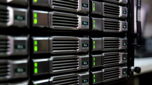 Close-up of 4TB hard drives in a server rack, green lights indicate active status. Perfect for showi