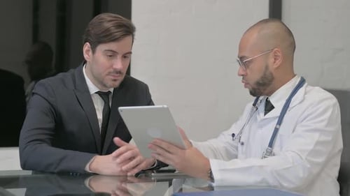 Doctor Showing Tablet to Patient in Office