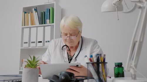 Médico que consulta a los pacientes en línea utilizando una tableta en el trabajo en el hospital.