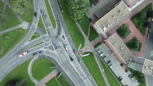 Drone footage bird's-eye view of a bustling intersection. Cars and trucks navigate the roads as pede
