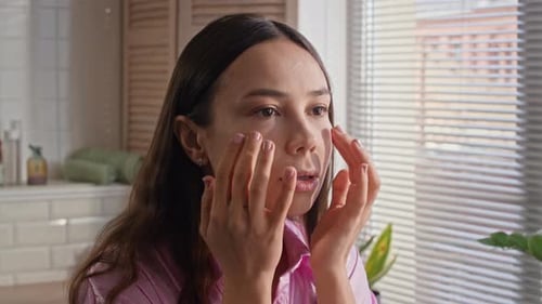 Young Woman Applying Moisturizer To Her Face