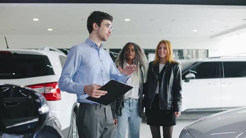 Two Women a Lesbian Couple Explore a Car Dealership with a Male Salesperson Learning About Vehicle